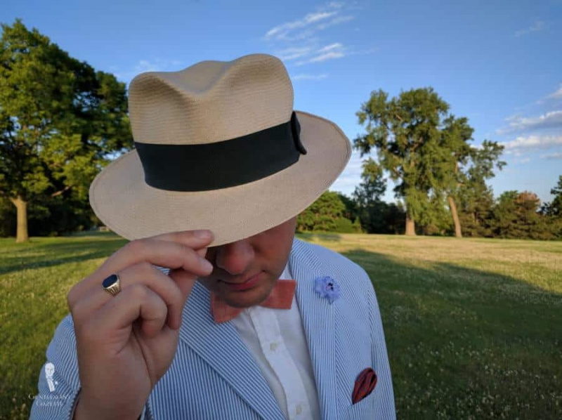 Chapéu Panamá com gravata borboleta de linho laranja, alfinete de lapela na lapela e lenço de bolso por Fort Belvedere