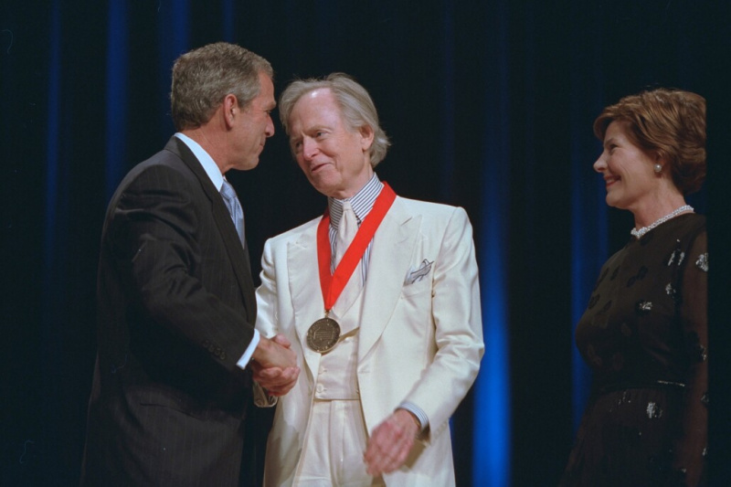 Новинар Том Волф, у свом белом оделу са потписом, прима медаљу за уметност и хуманистичке науке од председника Џорџа Буша В.