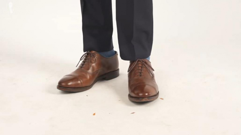 Une chaussure oxford marron moyen avec un v sur la languette.