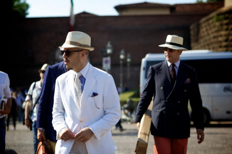 Blazer branco, de gravata branca, palha, chapéu de aba curta e óculos de sol no bolso