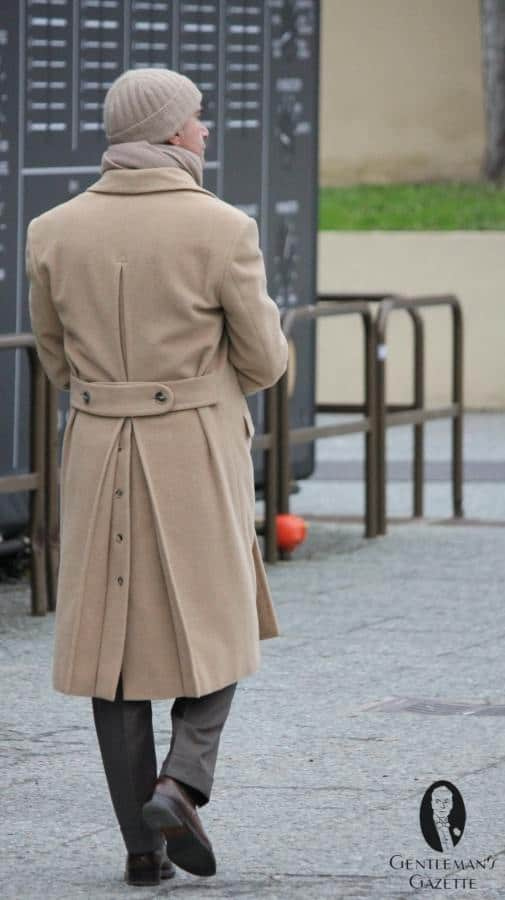 Fotografie muže, který odchází a ukazuje detaily kabátu
