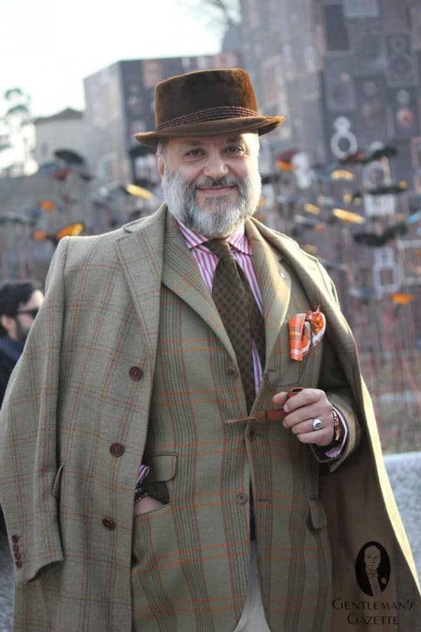 Uma fotografia de Gianni Fontana em uma roupa dominada por xadrezes verdes. Apenas a jaqueta ou o casaco funcionam bem, mas não os dois juntos