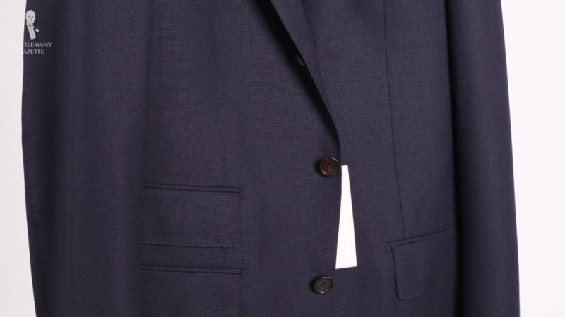 Un costume bleu marine à 3 boutons, avec le bouton du milieu fermé.