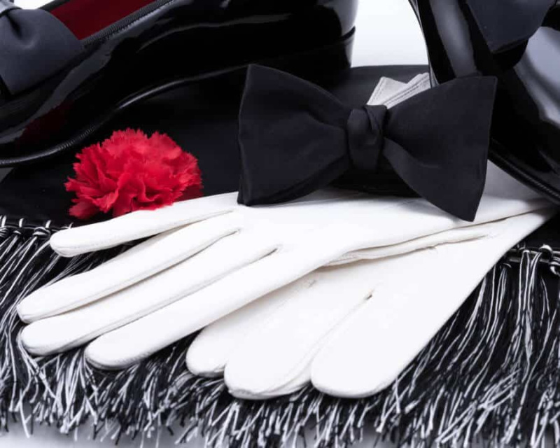Černý motýlek z hedvábného saténu s červeným karafiátem a večerním šátkem v černo-bílém hedvábném saténu a bílé kožené rukavice bez podšívky