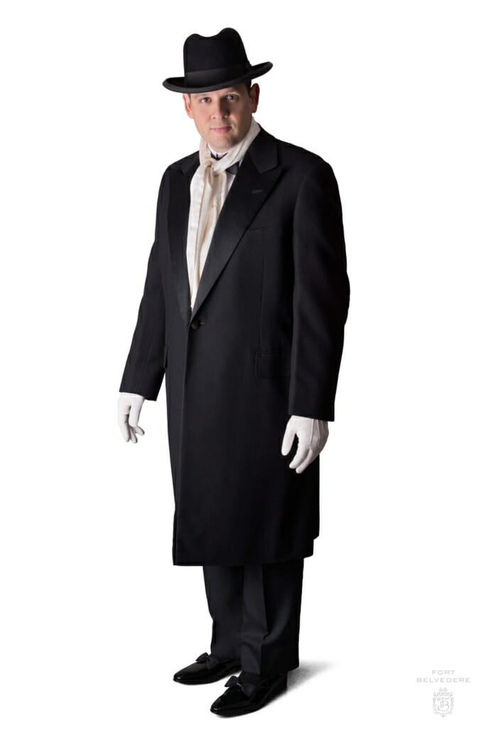 Večerní kabát s kloboukem Homburg, hedvábným šátkem a bílými rukavicemi ke smokingu s černou kravatou