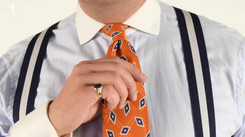 Raphael portant une chemise winchester, avec une cravate et des bretelles orange