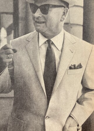 Mustavalkoinen valokuva puvussa olevasta miehestä, jolla on vihkisormus nimettömän kätensä nimettömässä sormessa