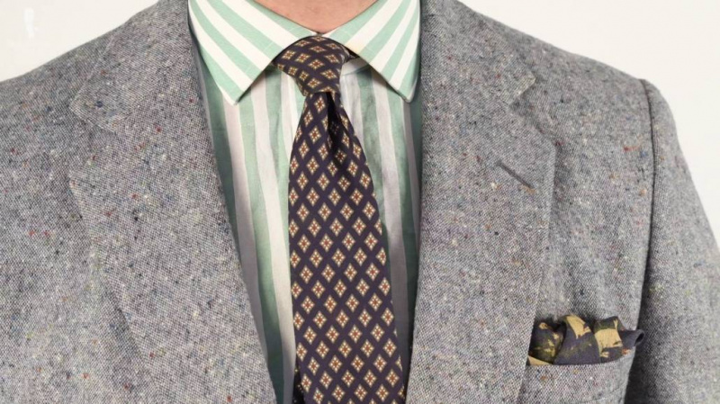La pochette de costume reprend le bleu et le beige de la cravate de cette tenue.