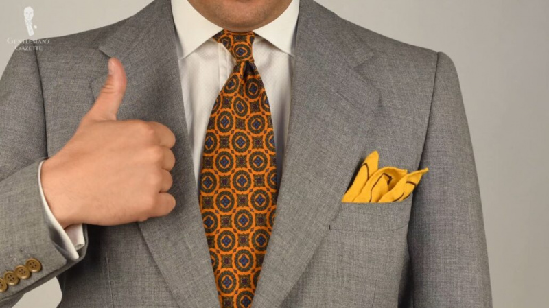 Raphael upřednostňuje pravidelné nošení kravat. [Na obrázku: Vlněná kravata Challis ve slunečnicově žluté barvě se zeleným, modrým a červeným vzorem z Fort Belvedere]