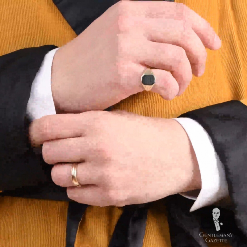 Fotografie páru rukou se zlatým snubním prstenem na levém prsteníčku a malíčkem na pravé ruce