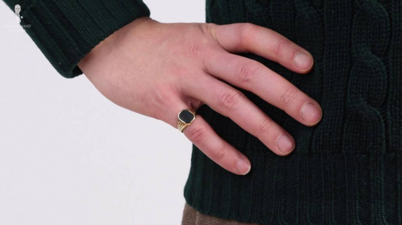 Фотографија руке на куку, са ружичастим прстеном на прсту