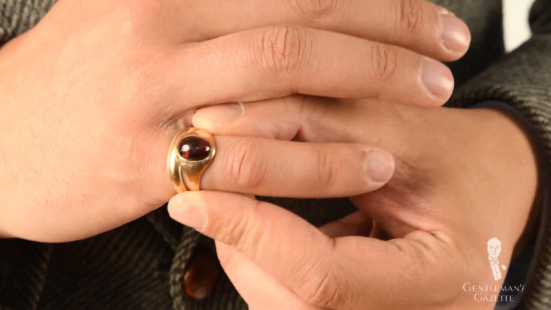 Zlatý prsten s červeným kamenem nošený na malíčku