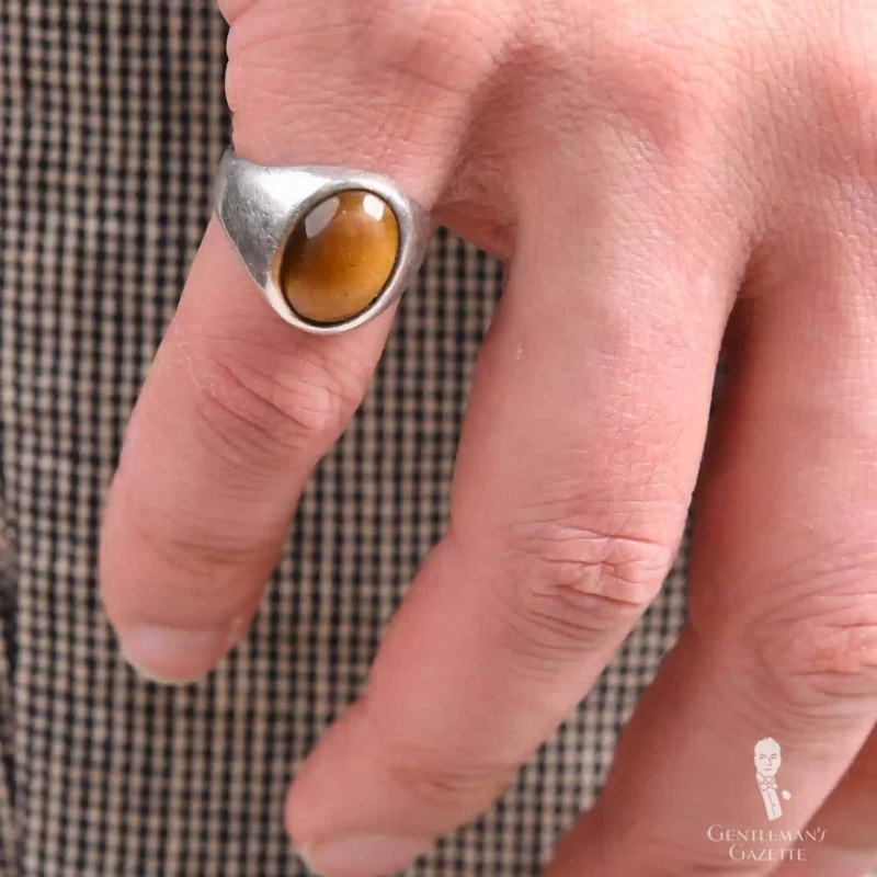 Фотографија сребрног прстена са каменом од ћилибара који се носи на ружичастом