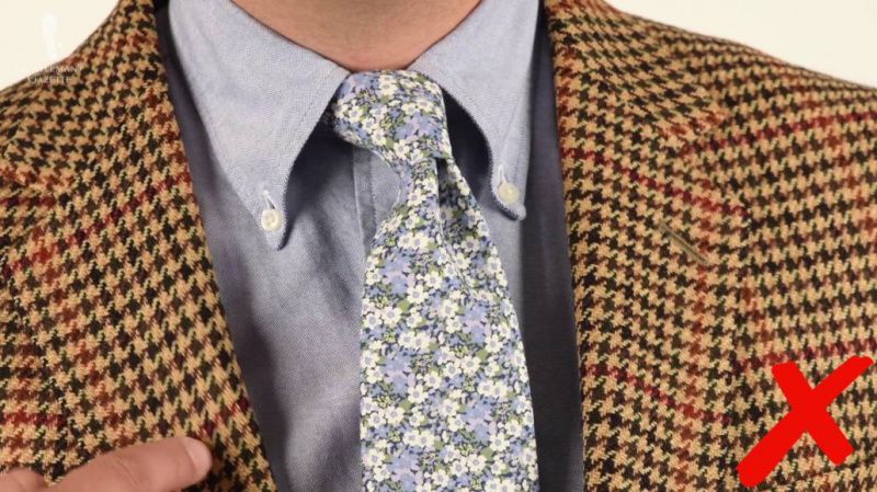 Raphael portant une veste pied-de-poule marron associée à une chemise OCBD gris clair et une cravate à fleurs bleu clair et blanche.