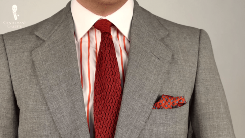 Une cravate texturée orange brûlé est un complément naturel à une chemise blanche à rayures orange.
