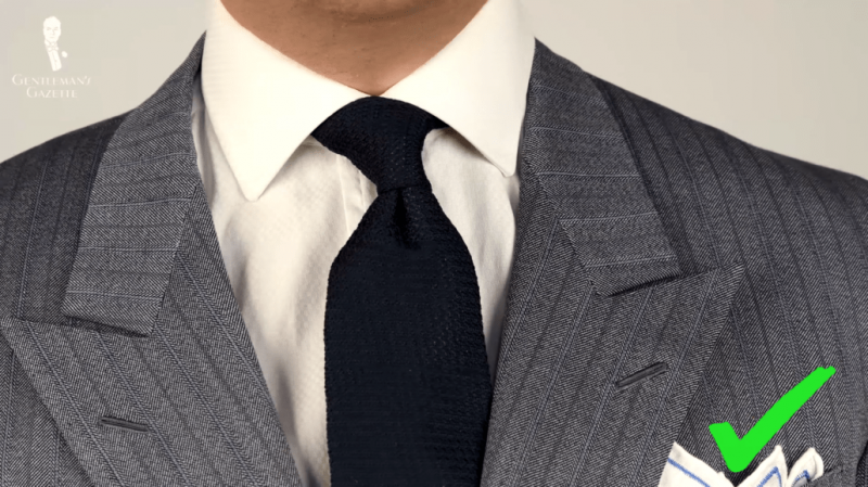 Este terno cinza listrado se beneficia de uma gravata de tricô mais casual em azul marinho e um lenço de bolso com debrum colorido.