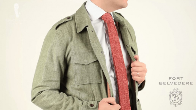 Zelené plátěné sako a bílá společenská košile doplněná pletenou kravatou ve melírované oranžové a hnědé barvě z Fort Belvedere.