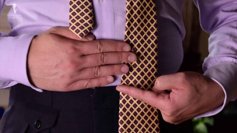 Raphael illustreert een goede startlengte voor de uiteinden van een stropdas ten opzichte van de tailleband voor het strikken.