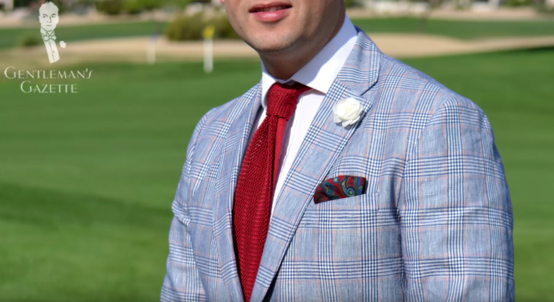 Raphael vestindo um casaco esportivo de verão xadrez Gagliardi Glen com gravata de malha em seda vermelha sólida, lapela branca spray rosa e Pocket Square de Fort Belvedere