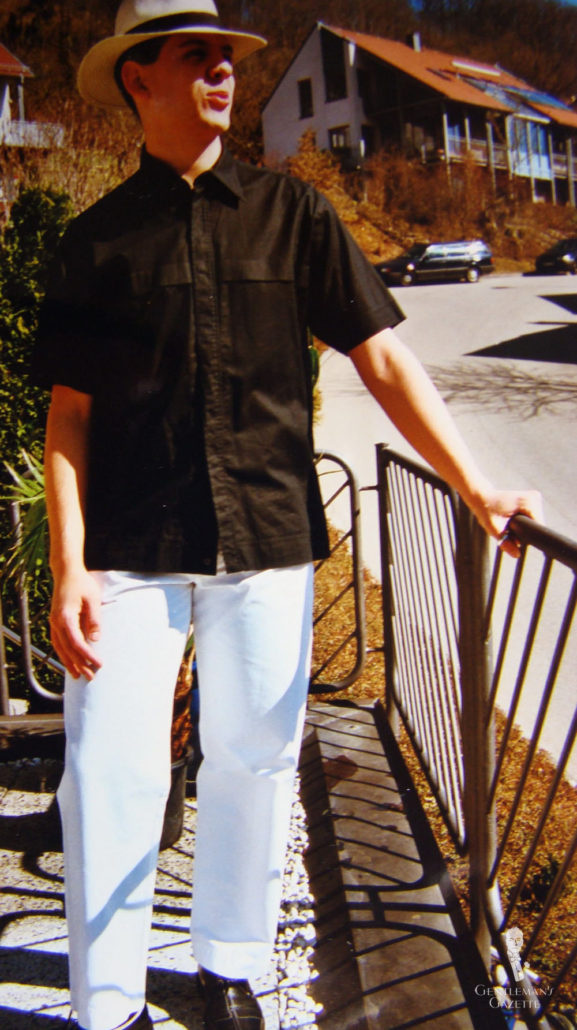 Um Raphael mais jovem em uma camisa preta de manga curta e chapéu Panamá