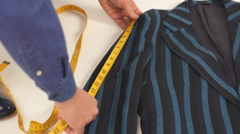Raphael mesurant une veste de costume à motifs