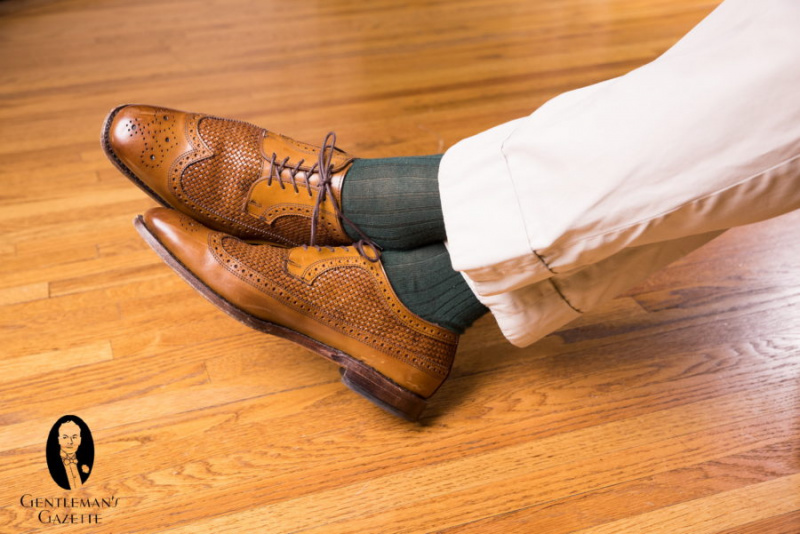 Смеђе ципеле за дерби са тамнозеленим и љубичастим ребрастим чарапама у сенци од тврђаве белведере са каки