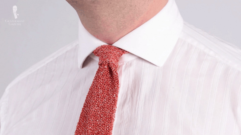 Un nœud de cravate à quatre mains, illustré ici avec la cravate en tricot chiné rouge orange Cri De La Soie Silk de Fort Belvedere