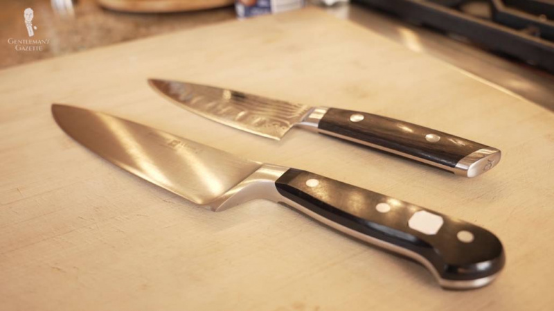 Duas facas de chef colocadas em cima de uma tábua de cortar.