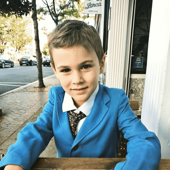 Emmett porte une veste et une cravate bleu vif avec un imprimé géométrique adapté à son âge.