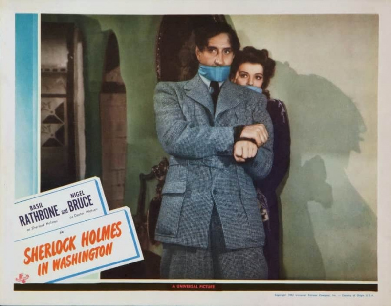 Basil Rathbone dans le rôle de Sherlock Homes en costume noir et blanc en tweed Norfolk