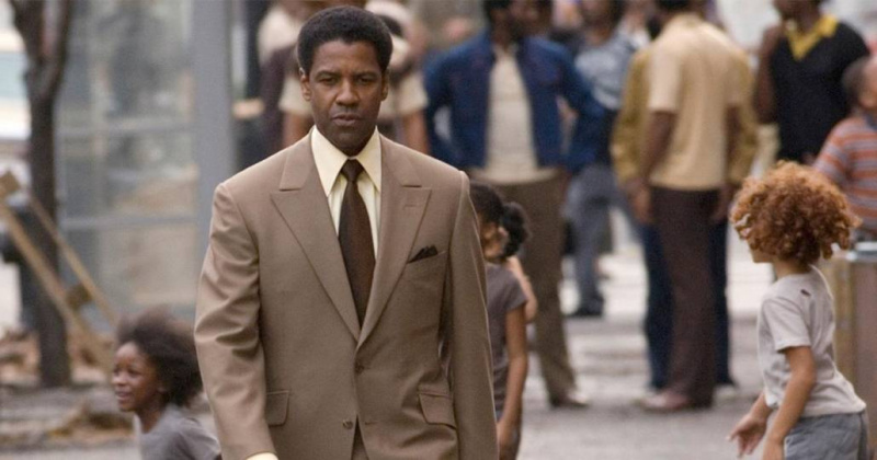 Denzel Washington na sobě hnědý oblek s hnědou kravatou.