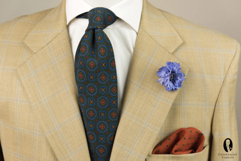 Tamsus, subtiliai margintas kaklaraištis padeda įžeminti šį šviesesnės spalvos, raštuotą švarką