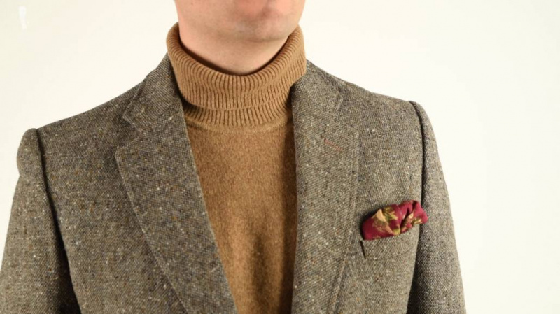 Une pochette en laine et soie à motif animalier associée à une veste en tweed et un pull à col roulé.