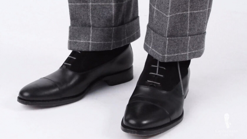 Pár černých bot Balmoral s šedými tkaničkami a šedým oblekem