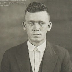 Černobílá fotografie muže s mírným podříznutím pompadour.
