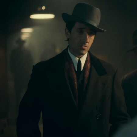 Peaky Blinders のキャラクターである Luca Changretta は、スカーフとフェドーラ帽が付いたオーバーコートを着ています。