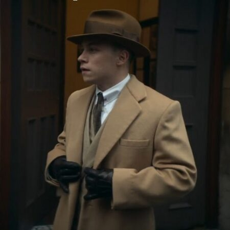 Peaky Blinders のキャラクター、マイケル・グレイは茶色のフェドーラ帽をかぶり、ラクダの毛のコートを着ています。