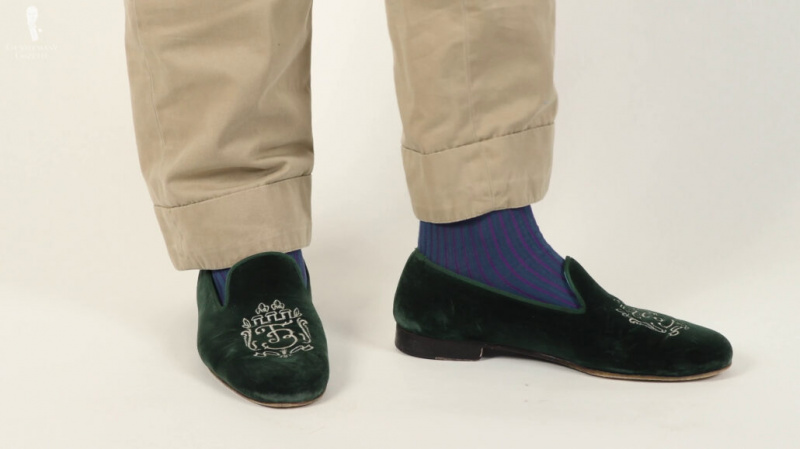 Os chinelos de veludo verde de Raphael combinados com meias listradas de sombra em verde-azulado e roxo de Fort Belvedere.