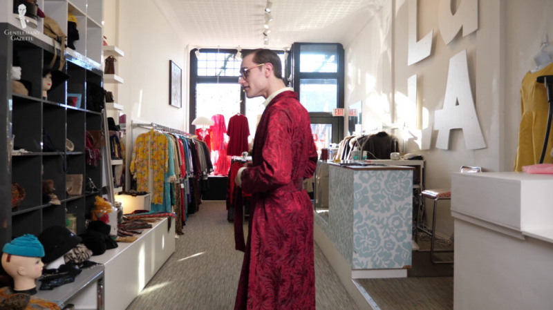 Preston essayant une robe de chambre en soie bordeaux vintage dans un magasin vintage.