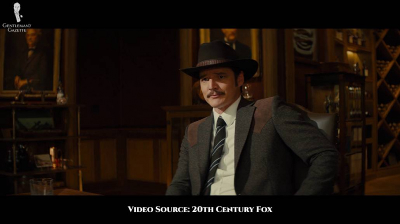Agente Whisky con una giacca western nera, un cappello nero, una camicia bianca e una cravatta granatina nera.