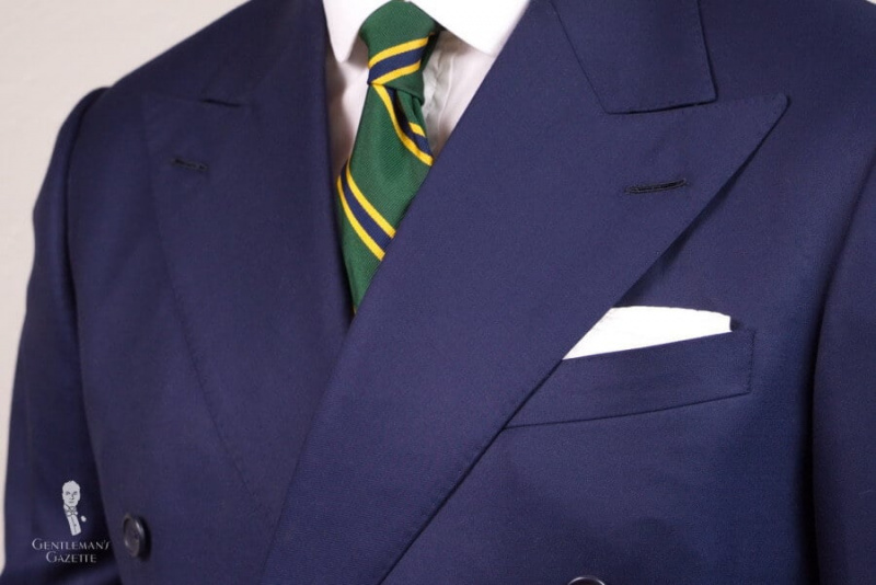 Тамноплаво одело са пругастом краватом и квадратним џепом на преклоп за ТВ