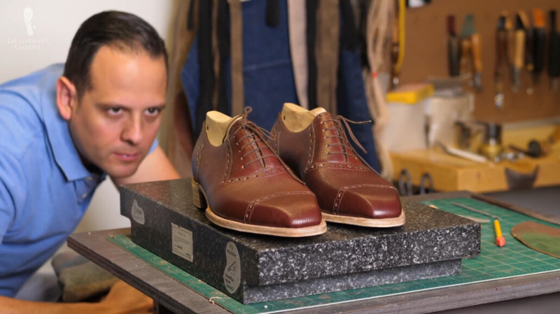 Raphael inspectant de près les détails de ses chaussures sur mesure.