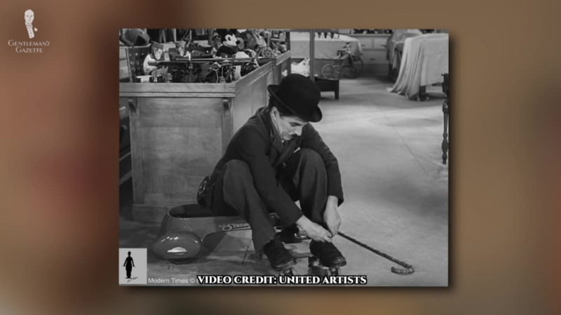 Een scène uit een film waarin Charlie Chaplin zijn rolschaatsen repareert.