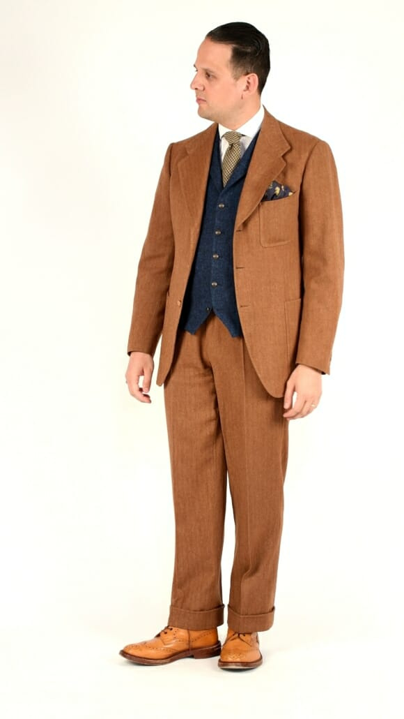 Sven Raphael Schneider portant un costume à chevrons de couleur rouille avec un gilet contrastant et des bottes richelieu marron clair