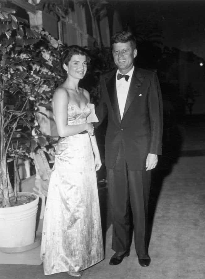 JFK en cravate noire avec des escarpins en cuir verni