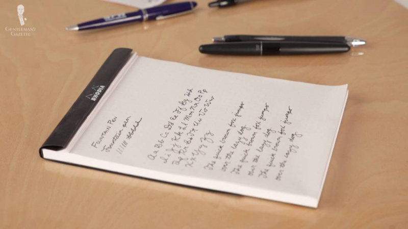 écriture manuscrite sur un bloc-notes avec quelques stylos-plumes éparpillés sur le côté