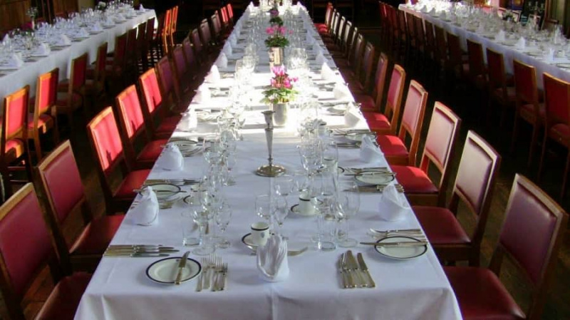 Coloque as configurações em um grande jantar formal. O anfitrião e a anfitriã podem estar sentados em outra mesa