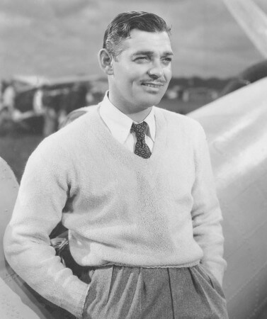 Clark Gable portant un pull à col en V et une cravate à micro-motifs imprimés avec un pantalon taille haute plissé gris
