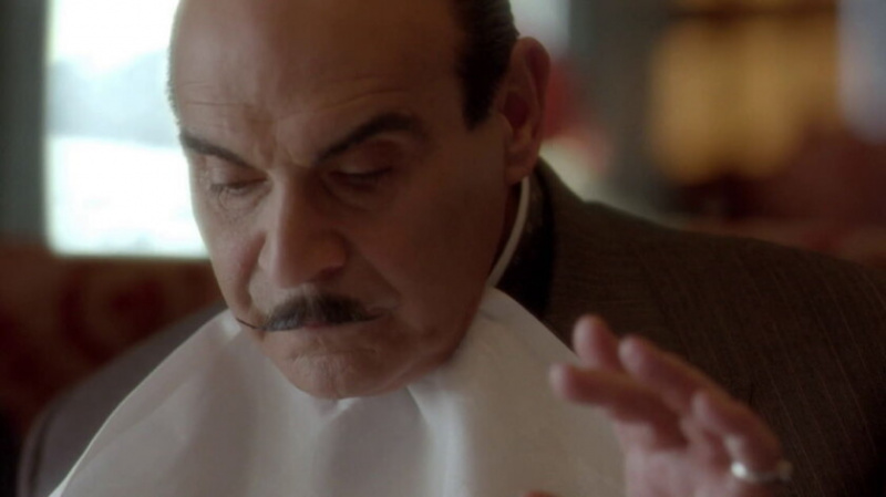 Poirot mangeant avec une serviette
