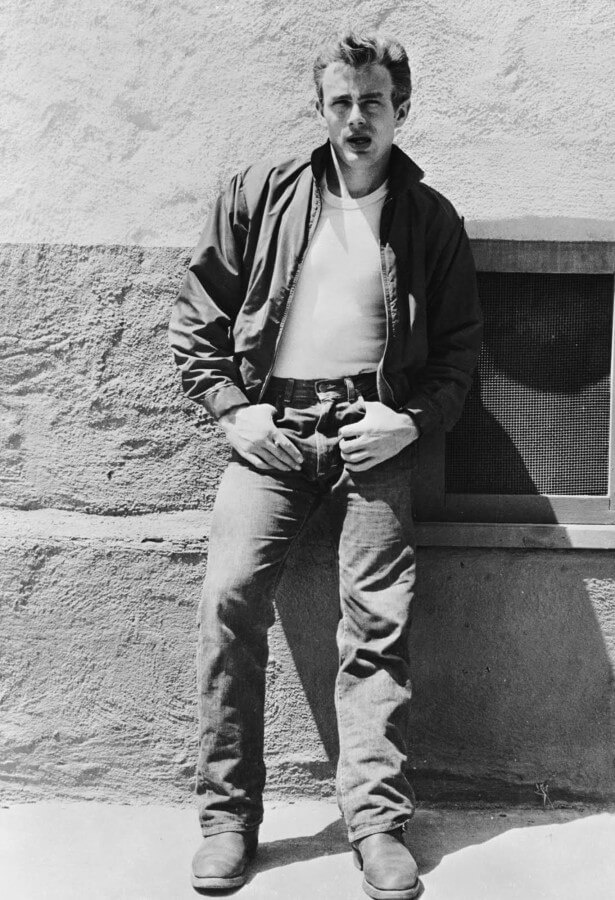 James Dean em Rebel Without a Cause, ostentando seu conjunto icônico de jaqueta Harrington vermelha, camiseta branca, jeans e botas.